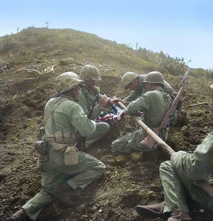 Soldiers in a trench during a historical event, assembling a flag, providing a new perspective on famous times.