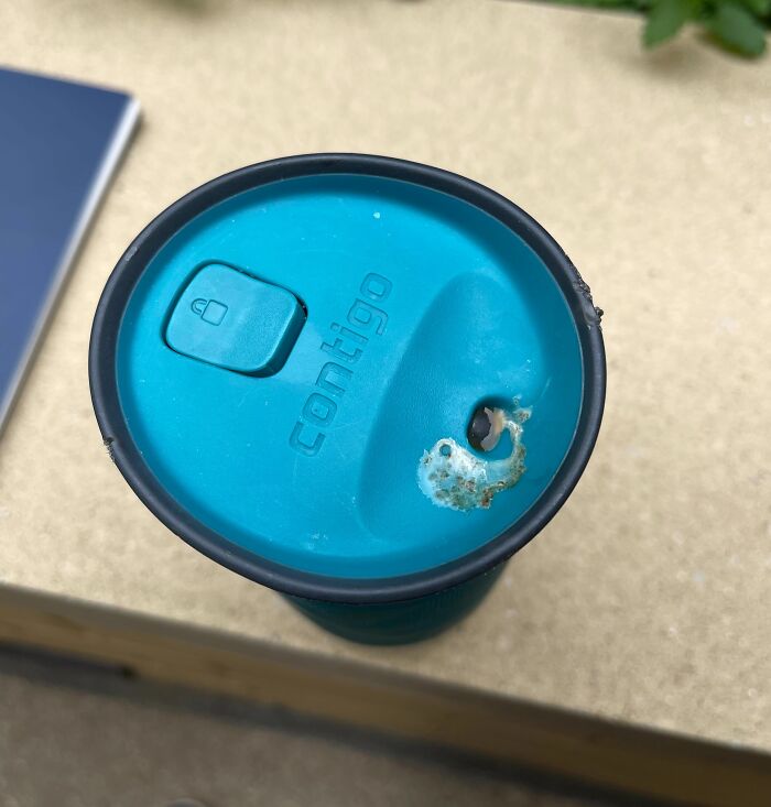 Taza reutilizable con tapa dañada y agujero, ejemplo de personas que seguramente estén teniendo un mal día.