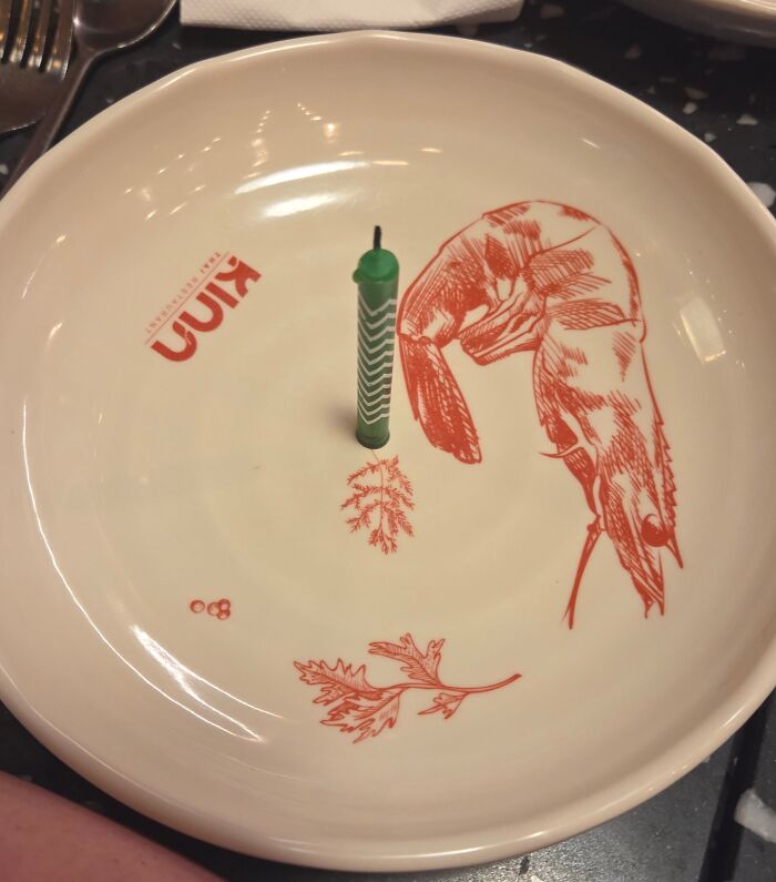 Empty plate with shrimp illustration and a single green candle.