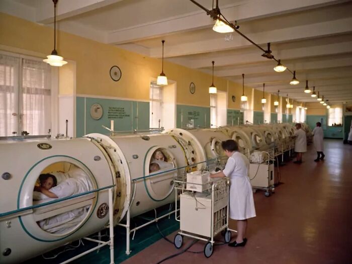 Hospital ward with patients in iron lungs, showcasing old medical technology shared by history enthusiasts.
