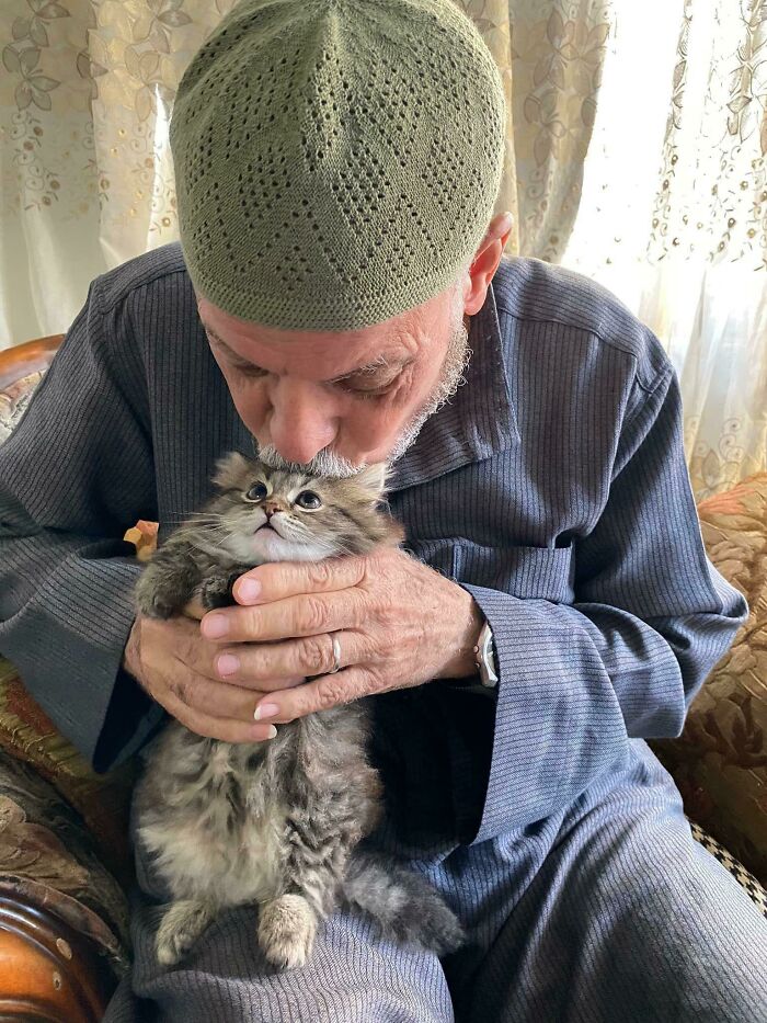 Man lovingly holding a fluffy cat, providing a glimpse of purrfect companionship.