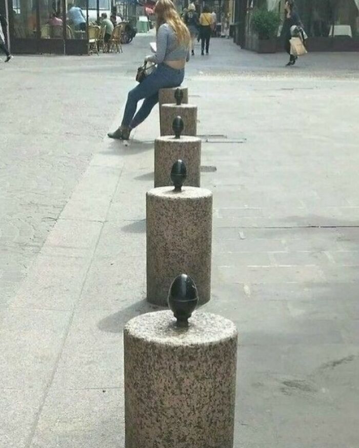 Person sitting creatively on stone post in urban setting, showcasing quirky content from popular IG page.