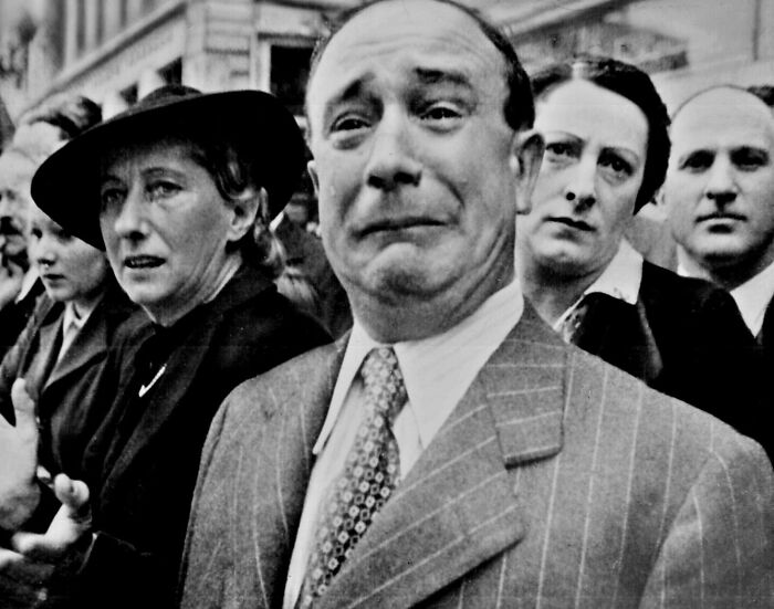 Emotional faces of civilians during a pivotal WWII moment captured in black and white photography.