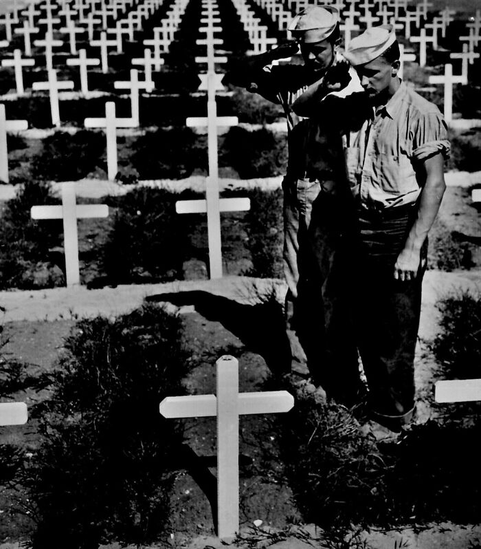 Two soldiers salute at a military cemetery, creating a poignant WWII photography moment.