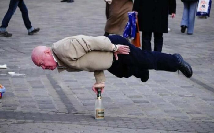 Man skillfully balances sideways on a bottle in public, showcasing a difficult post from an IG page.