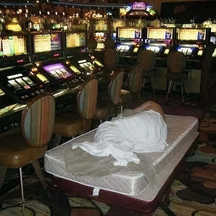 Person sleeping on a mattress in front of slot machines inside a casino, showcasing one of the hardest posts from IG.