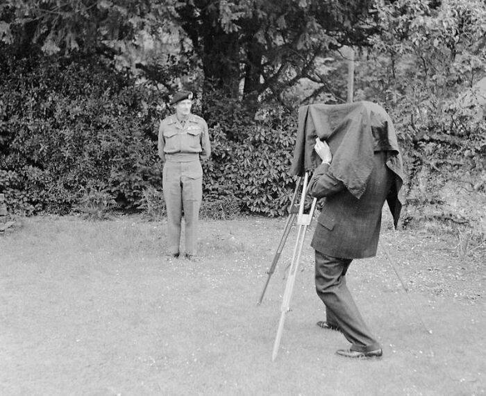 Soldier posing for a photographer with vintage camera setup during WWII, capturing an unforgettable moment.