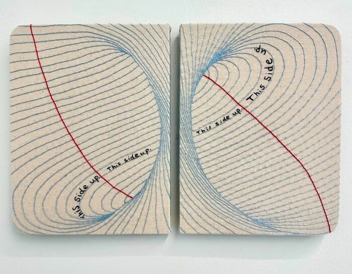 Fabric embroidered to resemble notebook pages with text "This side up" in blue and red threads.
