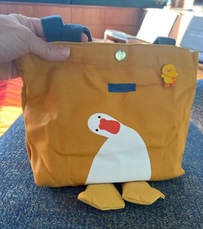 Yellow duck-themed tote bag with a playful design, held by a person.