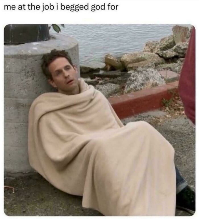 Person wrapped in a beige blanket sitting outdoors, captioned "me at the job I begged God for." Humorous work meme.