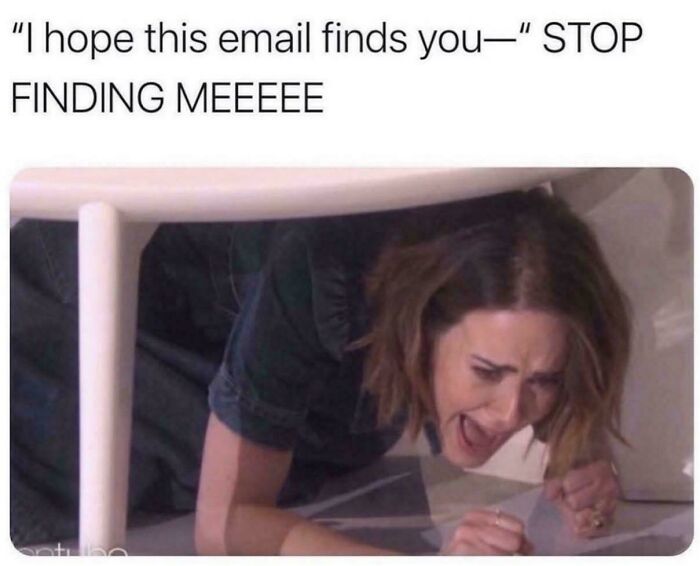 A woman hiding under a table with a caption about relentless emails, representing a funny work meme.