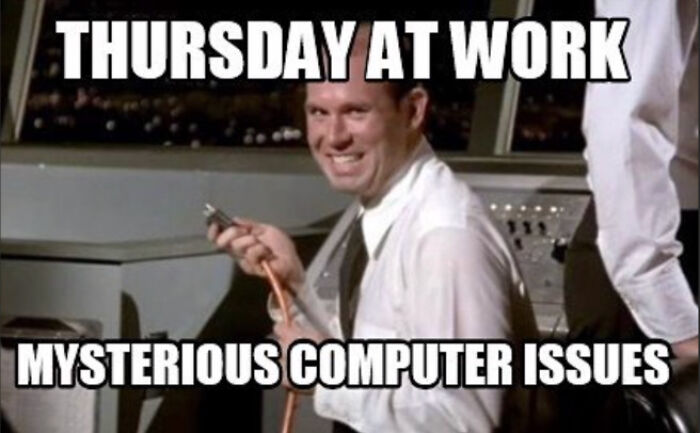 Smiling man at work holding cables, captioned "Mysterious Computer Issues," depicting a funny work meme.