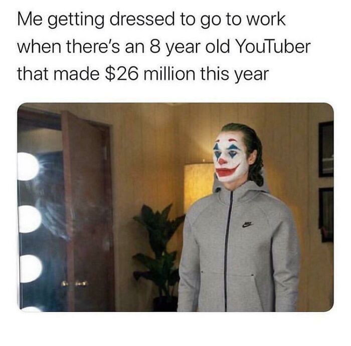 Person in clown makeup wearing a hoodie, standing in a room, reflecting on amusing work memes.