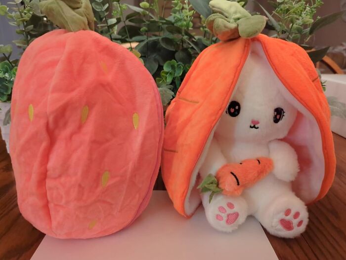Adorable Easter treasure: plush bunny in carrot costume, holding a tiny carrot, next to plush strawberry.