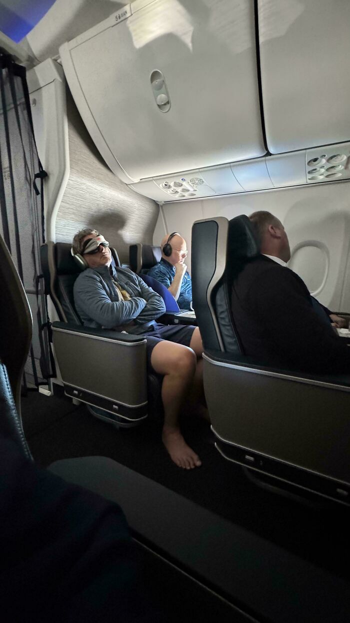 Passengers on a plane display no self-awareness; one is barefoot, another wears an eye mask and sleeps.