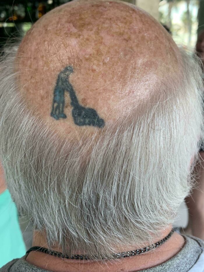 Bald man with tattoo of a person pushing a mower on his head, showcasing elderly humor.