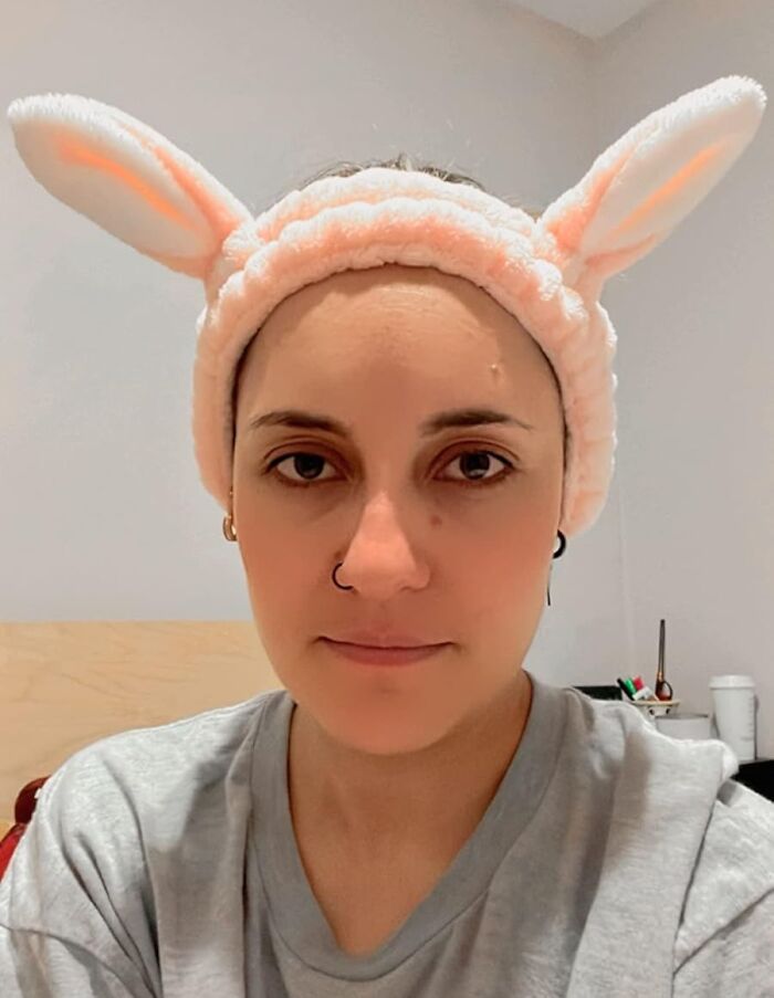 Person wearing a fluffy headband with bunny ears, smiling in an indoor setting, symbolizing Easter treasures.