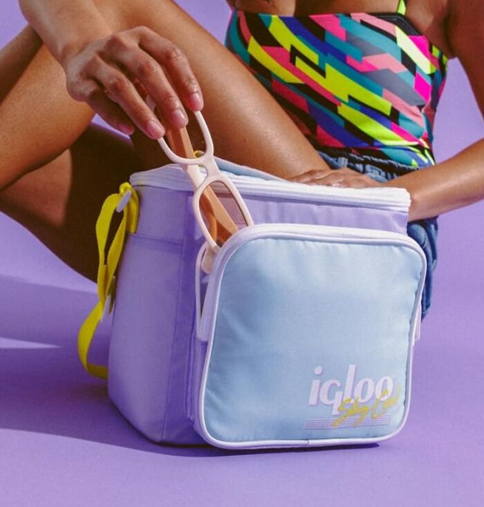 Person placing sunglasses into a pastel cooler bag, wearing a colorful swimsuit. Easter treasures excitement theme.