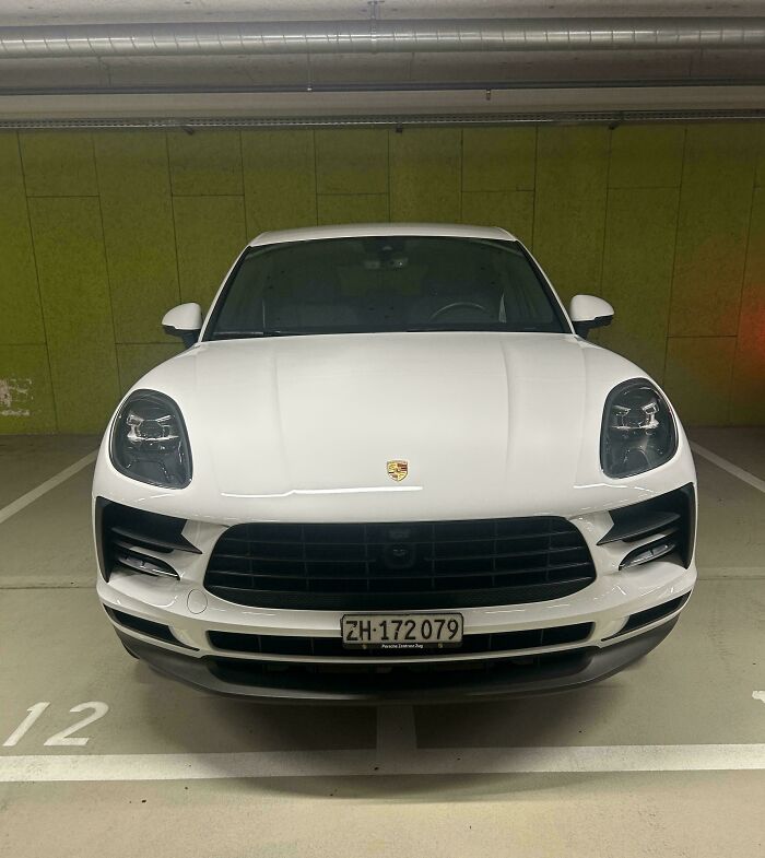 White Porsche parked across two spaces in a garage, illustrating lack of self-awareness.