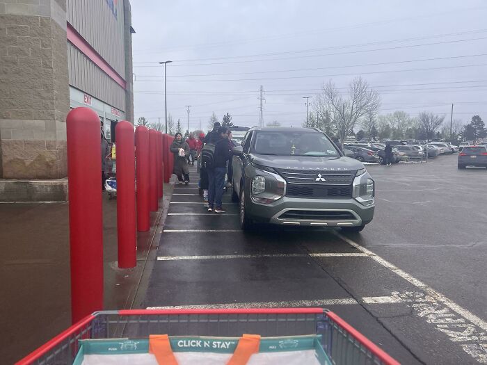 A car parked poorly outside a store with people nearby, highlighting lack of self-awareness in public spaces.