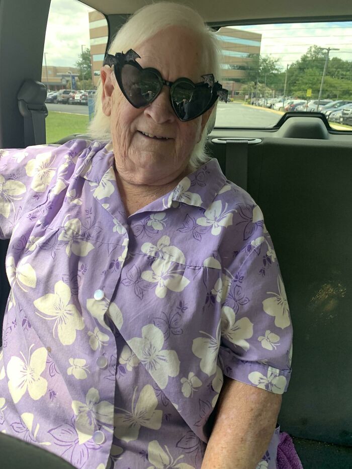 Elderly person wearing heart-shaped sunglasses and a floral shirt, showcasing humor and style.