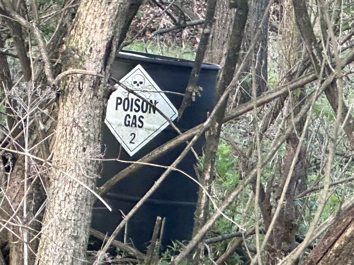 Dangerous scene: Barrel labeled 'Poison Gas' amidst trees and foliage.