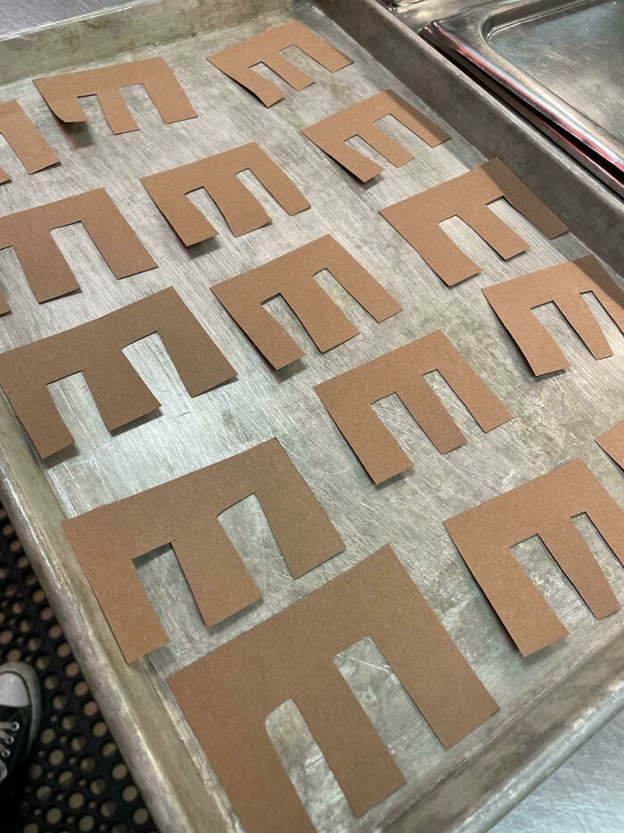 Brown paper E's arranged on a baking tray as a humorous prank by a creative coworker.
