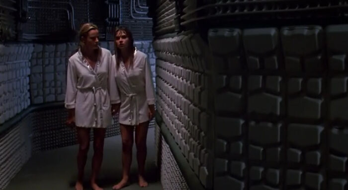 Two actors in white robes walk through a sci-fi corridor, showcasing creative use of film props.