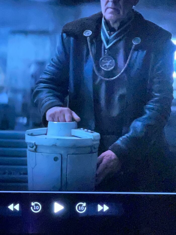 Man in dark coat interacting with a sci-fi prop in a dimly lit setting, showcasing creative filmmaking use of props.