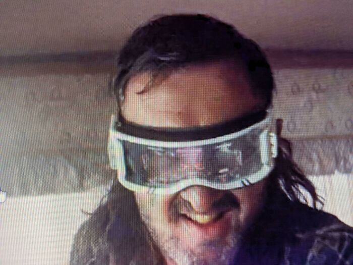 Man wearing creative filmmaking prop goggles, smiling indoors.