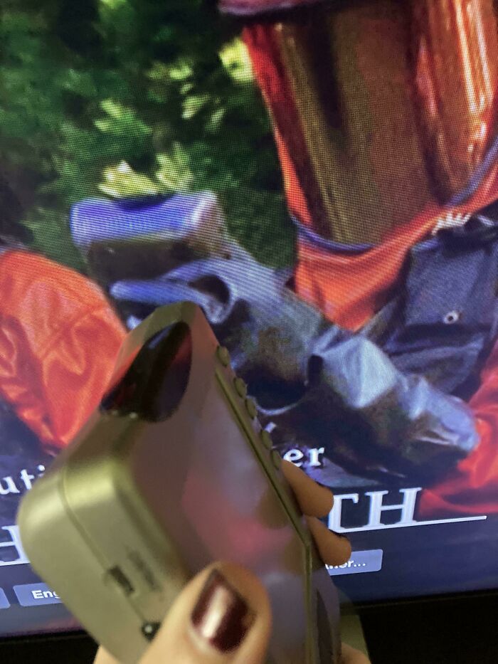 A handheld vacuum cleaner creatively used as a prop in a movie scene with a masked character in red and black attire.