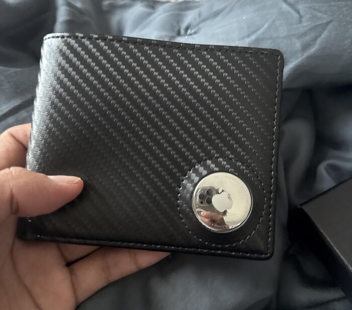 Hand holding a black carbon fiber wallet with an Apple logo, evoking millennial nostalgia.