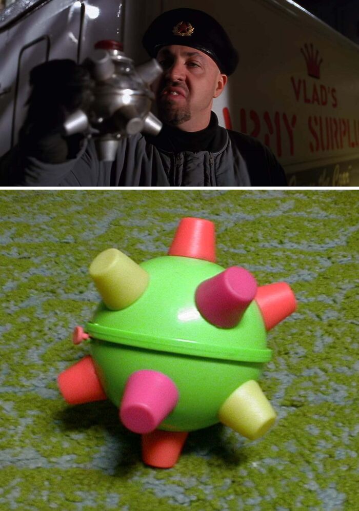 Man holding creative film prop resembling a futuristic device; similar to a colorful toy on a green carpet.