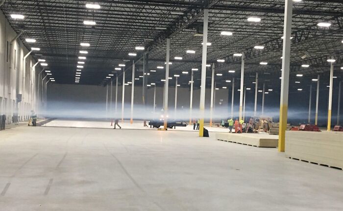 Warehouse with workers and low fog, creating a potentially dangerous work environment.