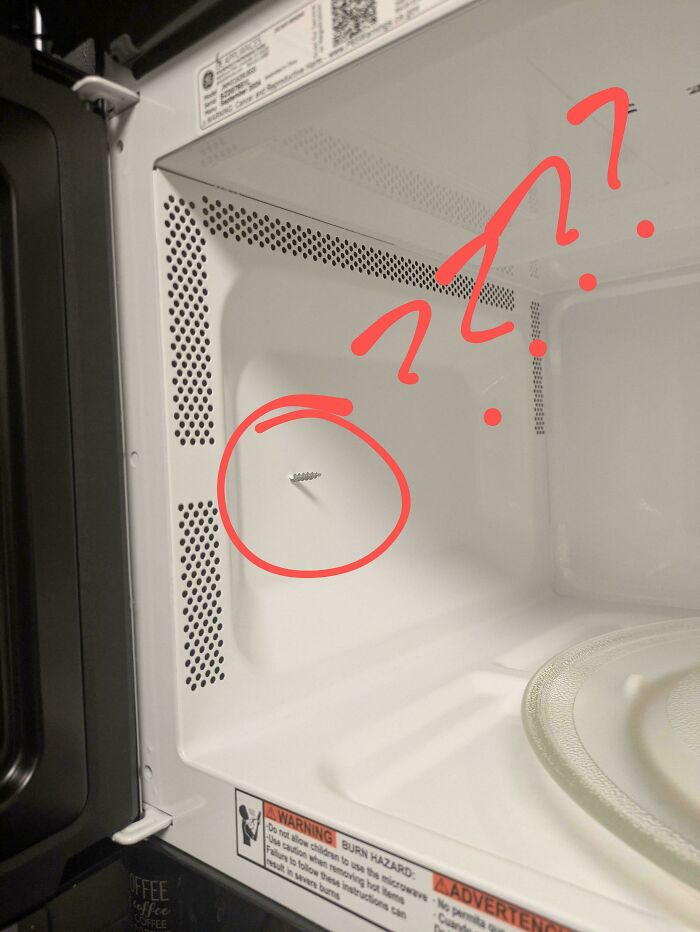 Microwave interior with a loose s***w awkwardly placed on the wall, highlighted with red annotations.