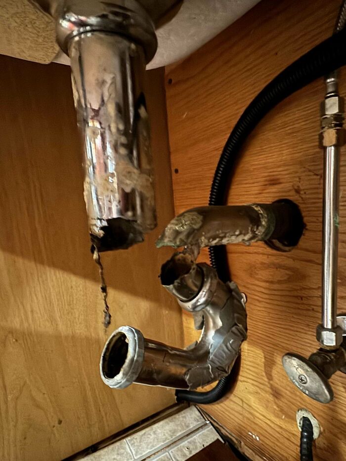 Damaged plumbing under a sink, showcasing issues with landlords.
