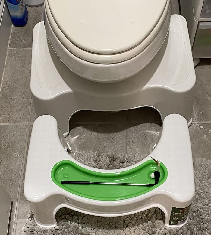Bathroom putting green next to a toilet, showcasing a ridiculous find for entertainment during bathroom breaks.