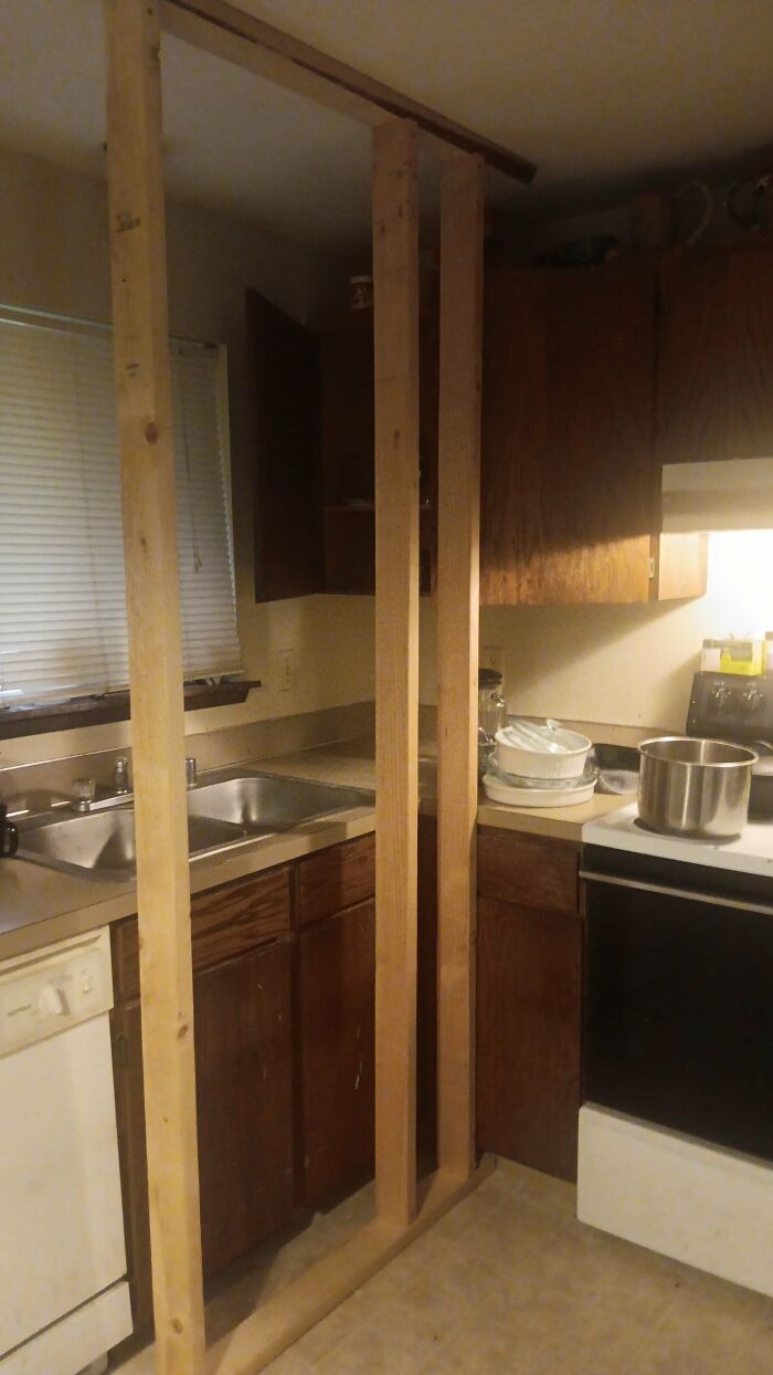 Kitchen view with wooden beams awkwardly built by landlords beside the stove and sink.