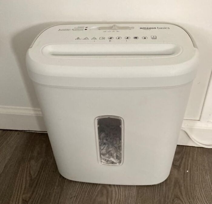 Amazon Basics paper shredder on a wooden floor, included in top review list.