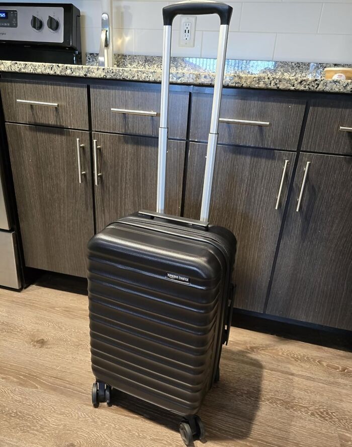 Black Amazon Basics suitcase with a retractable handle in a modern kitchen setting.