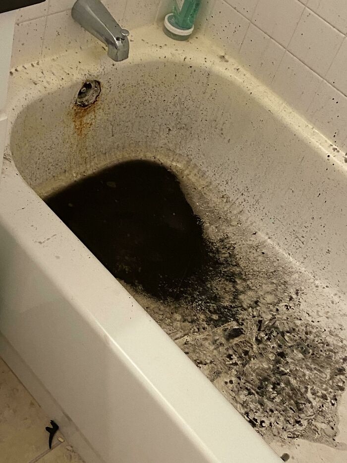 Dirty bathtub with black water and rust, illustrating issues caused by neglectful landlords.