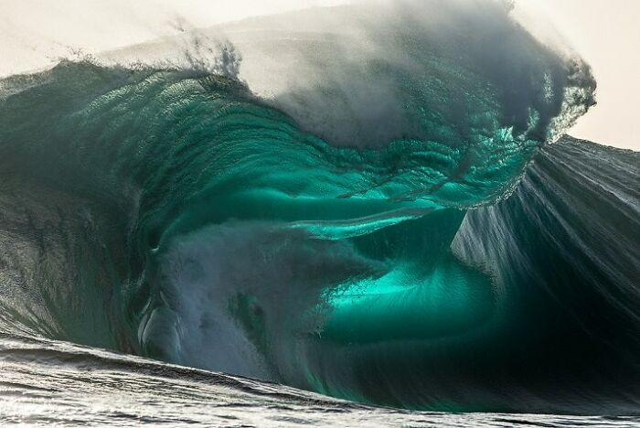 Massive, ominous ocean wave crashing with dark, turquoise hues, evoking a sense of fear.