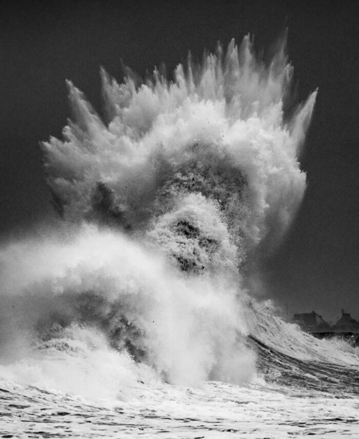 Dramatic ocean wave crashing, captured in black and white, showcasing the ocean's power and intensity.