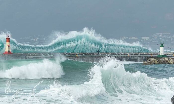 Massive ocean waves crashing over a pier, creating a dramatic and intimidating scene.