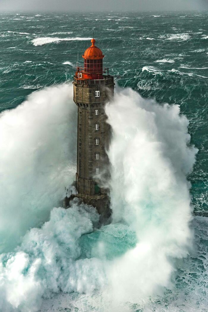 Lighthouse engulfed by massive ocean waves, showcasing the ocean's terrifying power.