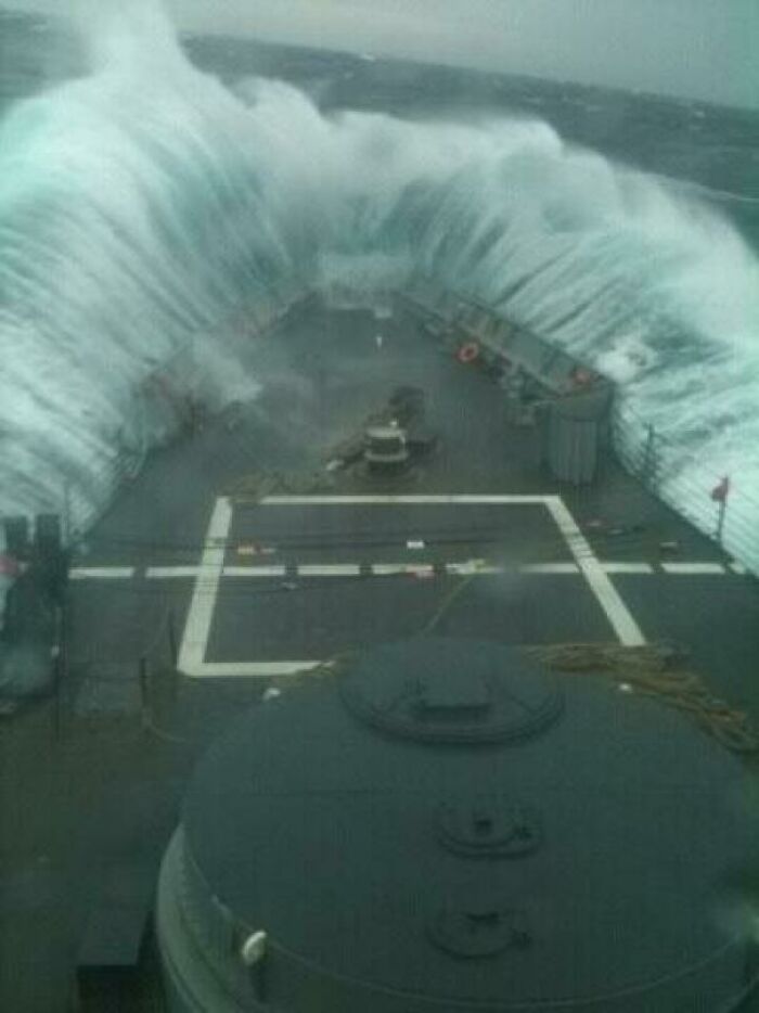 Massive ocean wave crashing over a ship's deck during a stormy sea voyage, highlighting ocean dangers.