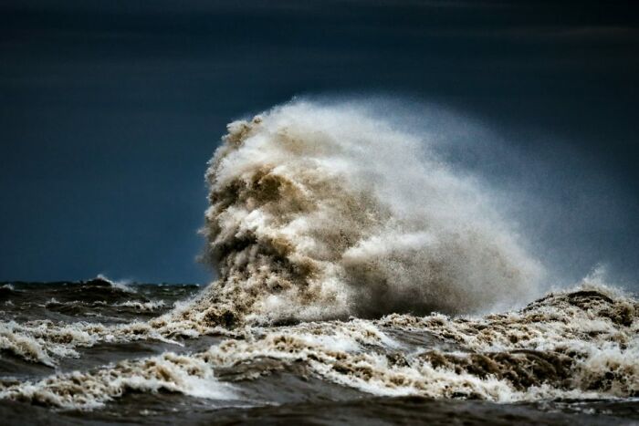 Powerful ocean waves crashing under a dark sky, showcasing nature's intense and scary force.