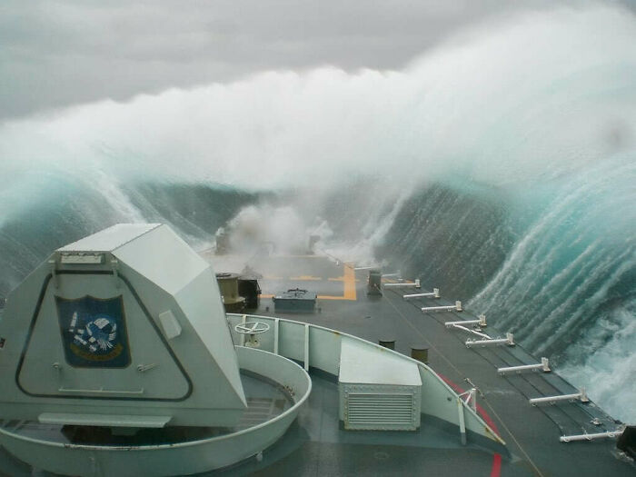 Massive wave crashing over a ship in the ocean, showcasing the power and fearsome nature of the sea.