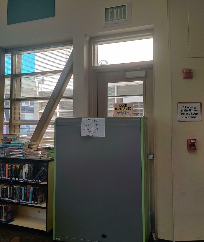 Library exit door blocked with a sign warning of danger, urging not to use it.
