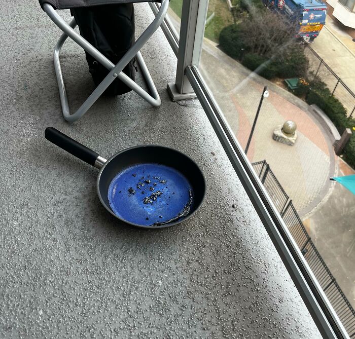 Frying pan with melted contents on a wet balcony, showcasing something dangerous.